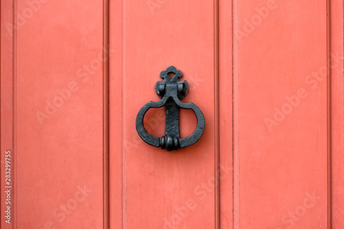 Bright red (carmin) wooden door with old door knocker. Closeup background