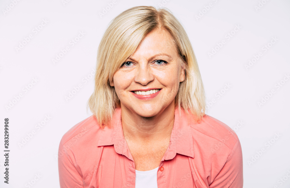 Close up portrait of happy smiling and beautiful blonde senior woman isolated in studio and posing with smile on camera Close up portrait of happy smiling and beautiful blonde senior woman isolated in studio and posing with smile on camera