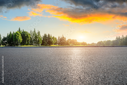 Country asphalt road and green woods nature landscape at sunset