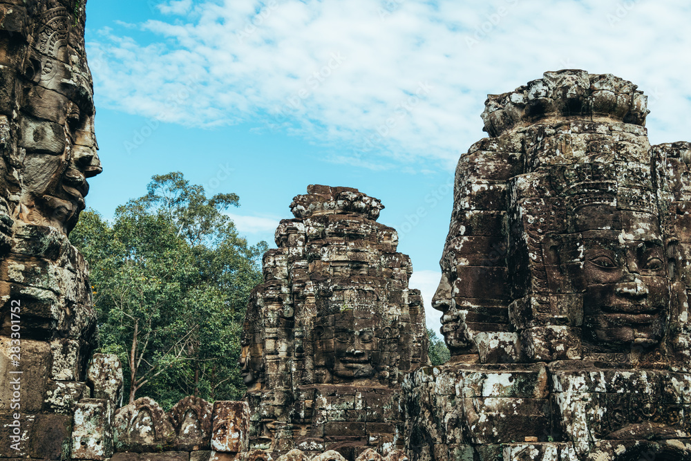 Three statues carved with face shapes on four sides on the roofs of the ruins of the Bayon temple in Ankgor Thom, Cambodia - UNESCO World Heritage Site 1992