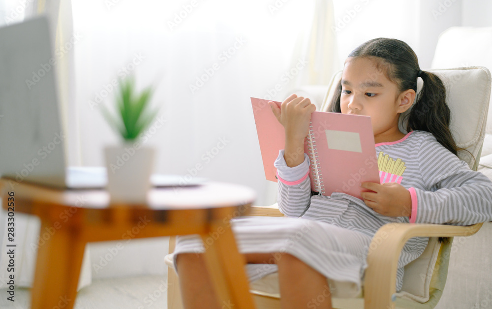happy child little asian girl reading a books on the table in the living room at home. family activity concept happy child little asian girl reading a books on the table in the living room at home. family activity concept