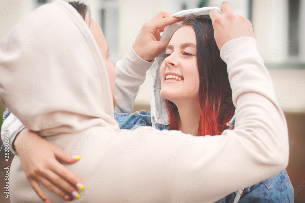 Naklejka premium Caring for each other. A young man puts a hood on a girl in the rain.