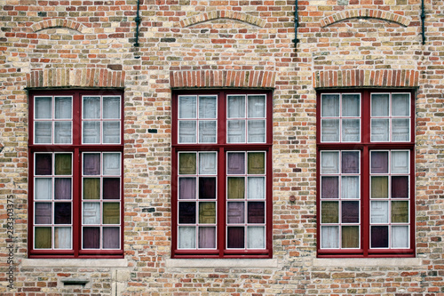 Old brick wall whith three windows with multi-colored glass