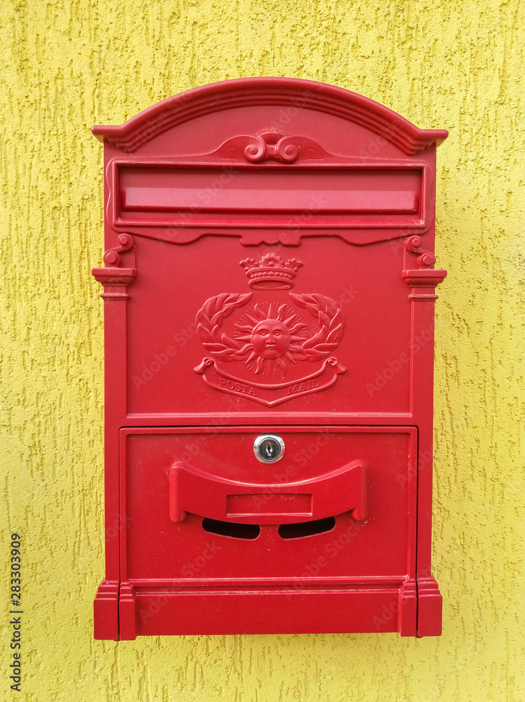 Red metal mailbox on a yellow wall
