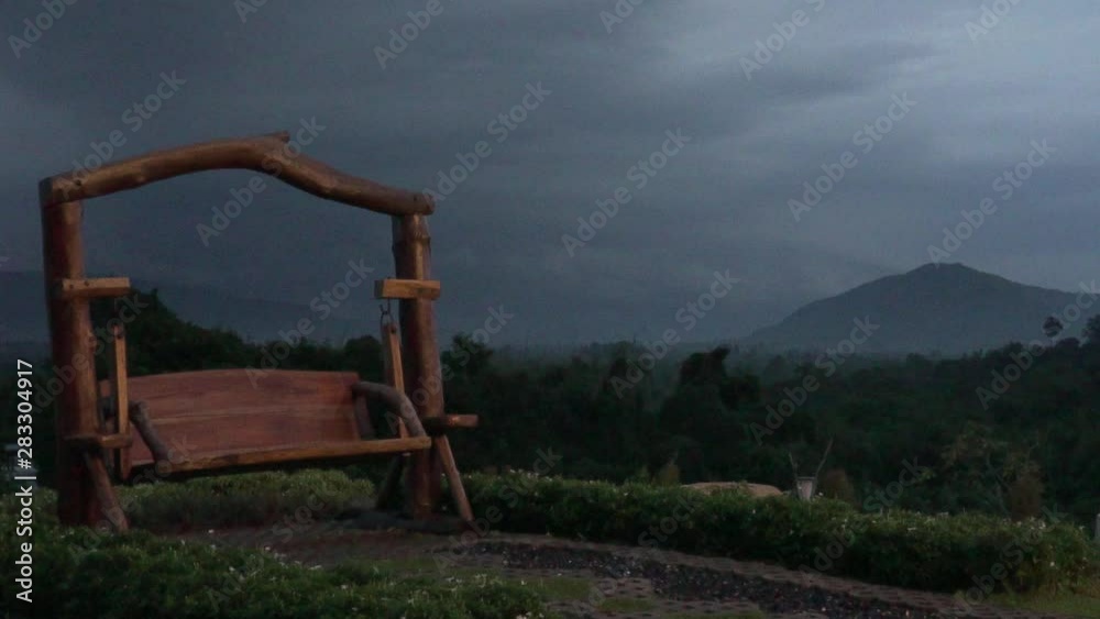 wooden porch swing in the mountain resort at sunset in pouring rain wooden porch swing in the mountain resort at sunset in pouring rain