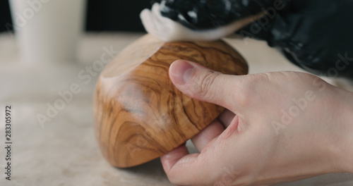 woodworker applying oil finish to olive wood bowl