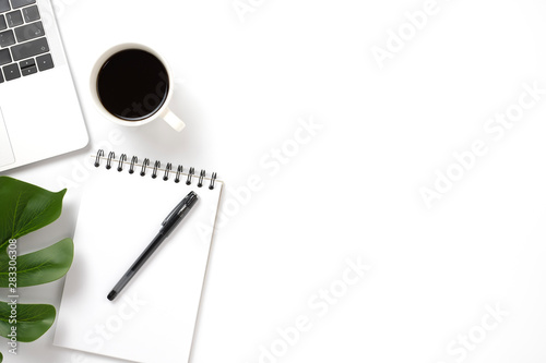 Flat lay, top view office table white desk. Workspace with notepad, pen, green leaf, and coffee cup on white background.