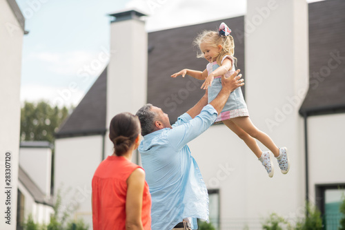 Lovely daughter feeling amazing while father lifting her