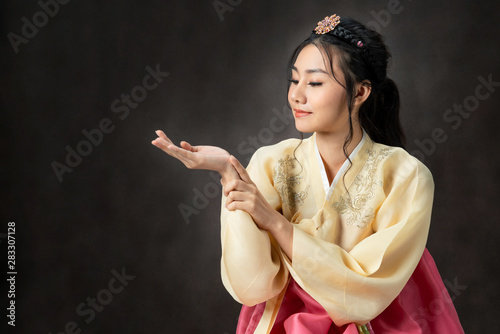 Korean woman wearing traditional korean dress (Hanbok) on black background in studio. Beautiful Korea culture. photo