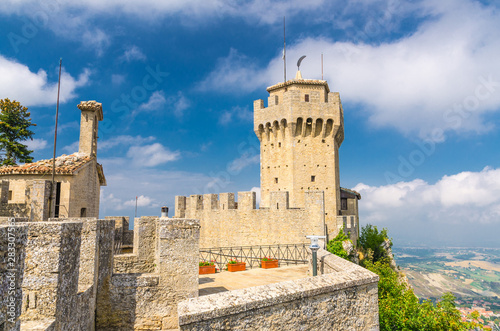 Republic San Marino Seconda Torre La Cesta second fortress tower with merlons and brick walls on Mount Titano stone rock, blue sky white clouds background photo