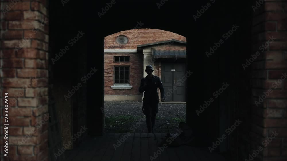An arch in an old red brick building. A German soldier with a gun going through the arch. WWII reenactment An arch in an old red brick building. A German soldier with a gun going through the arch. WWII reenactment