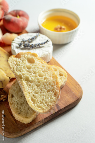 Top view different types of cheeses on wooden cutting board. Cheese with fig peach, honey, ciabatta and nuts, glass of red wine. Stylish food flat lay on grey background. Copy space. Soft focus