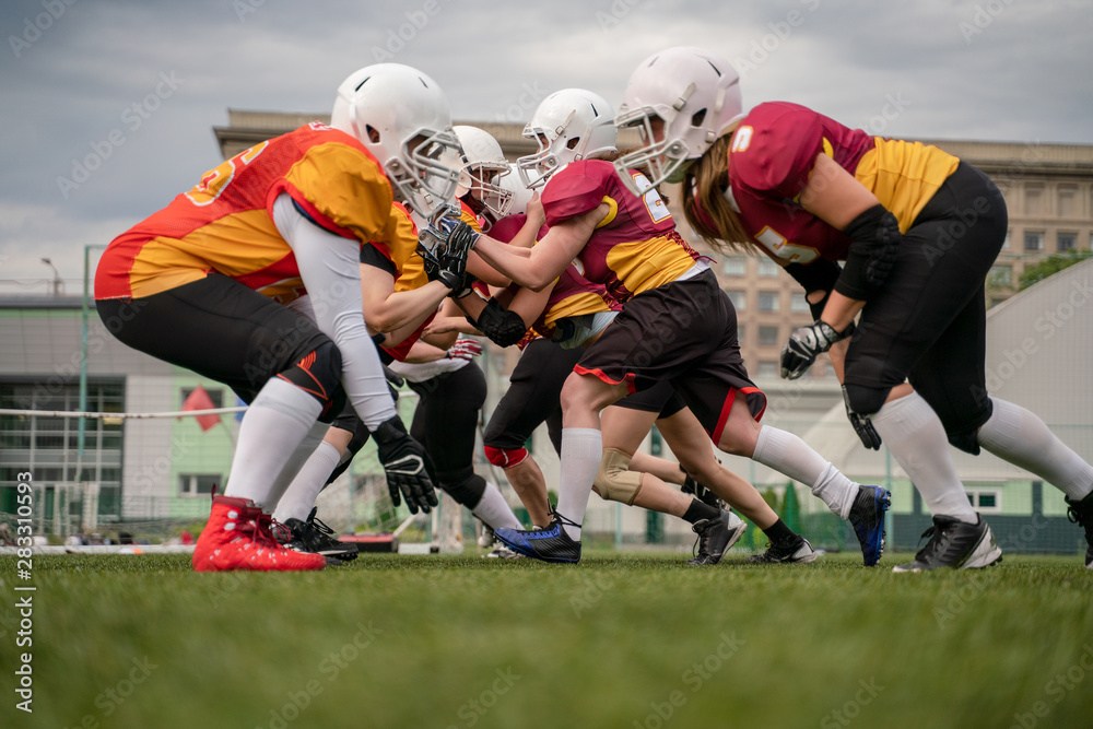 Photo of female team in helmets playing rugby on playground Photo of female team in helmets playing rugby on playground