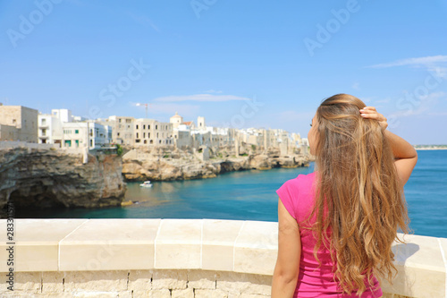 Summer holidays in Apulia. Back view of beautiful young woman enjoying Polignano a mare view, Mediterranean Sea, Italy. © zigres