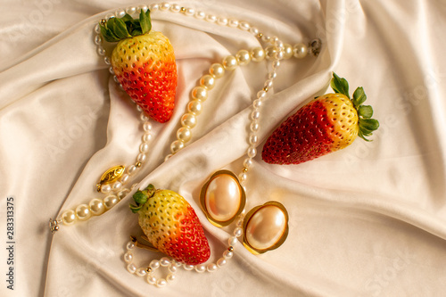 Pearl earrings and necklace on the sation dress with strawberries photo