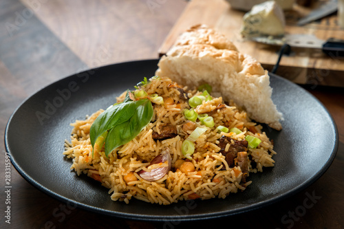 Traditional homemade Uzbek pilaf or plov on a wooden table concept of oriental cuisine. Selective Focus.