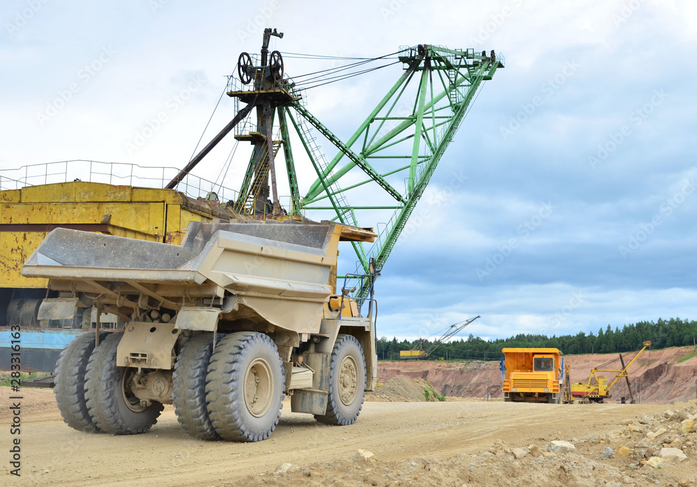 Huge mining excavator and dump trucks work in an open pit. Loading and transportation of sand, gravel, dolomite and limestone to the place of processing and crushing. Mining industry - Image Huge mining excavator and dump trucks work in an open pit. Loading and transportation of sand, gravel, dolomite and limestone to the place of processing and crushing. Mining industry - Image