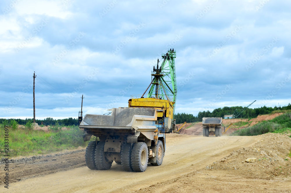 Big yellow dump truck working in the limestone open-pit. Loading and transportation of minerals in the dolomite mining quarry. Belarus, Vitebsk, in the largest i dolomite deposit, quarry 