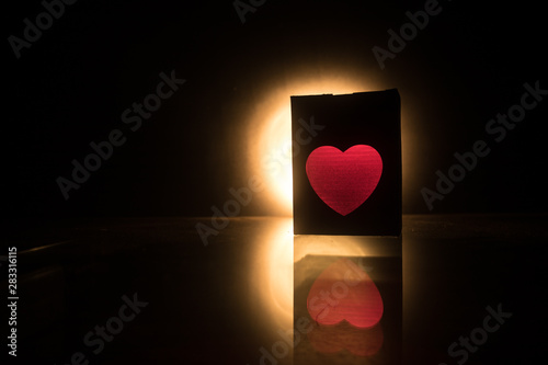 Blurred neon heart icon on a dark background. Copy space with red bright colorful heart on black background photo