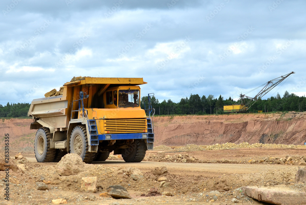 Big yellow dump truck working in the limestone open-pit. Loading and transportation of minerals in the dolomite mining quarry. Belarus, Vitebsk, in the largest i dolomite deposit, quarry 