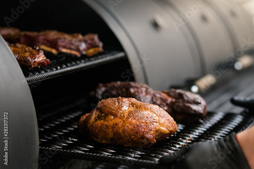Grill restaurant kitchen. Chef cooking poultry, beef and pork meat, ribs in BBQ smoker.
