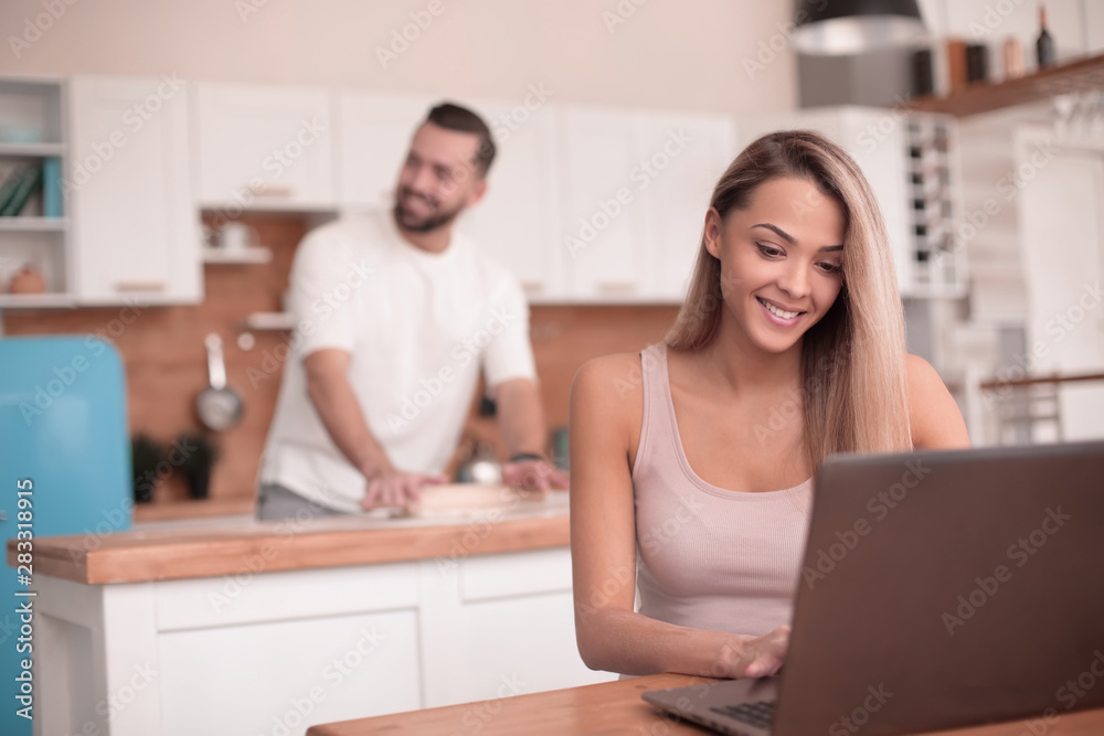 young woman working on laptop in kitchen young woman working on laptop in kitchen