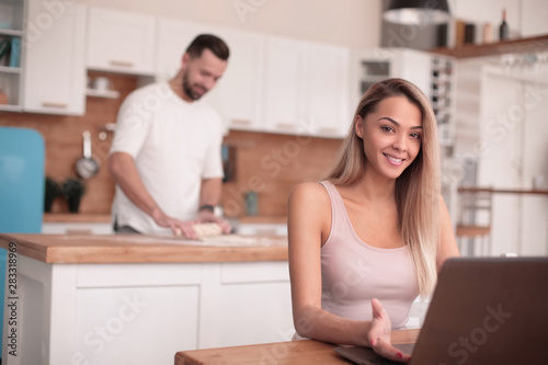 young woman sitting in front of open laptop in kitchen