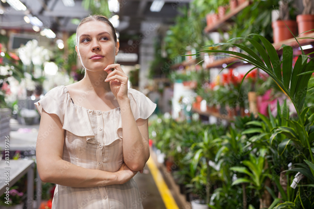 Fototapeta premium Portrait of woman chooses flowers in flower shop