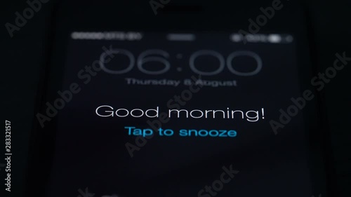 Good morning alarm clock on the phone in the dark room, close-up