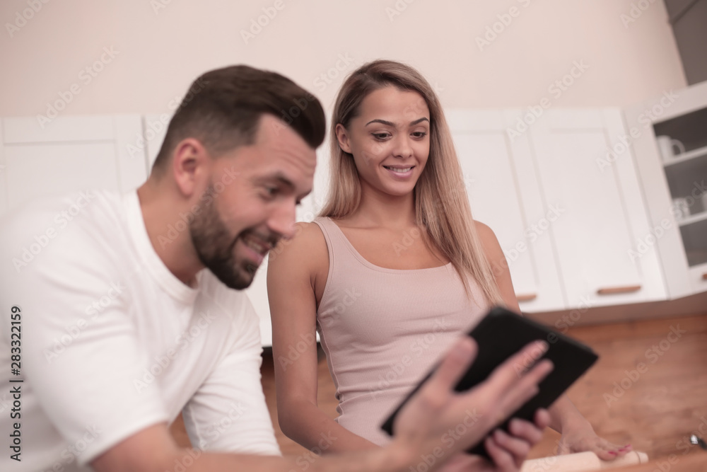Young couple surfing the web with tablet at home kitchen Young couple surfing the web with tablet at home kitchen