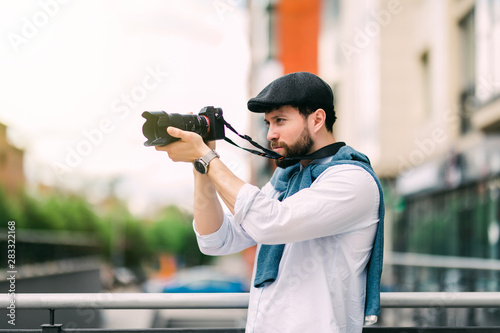 Young man with camera photographing at the street