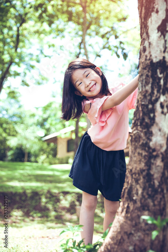 Cute little asian girl under big tree outdoor in the park.