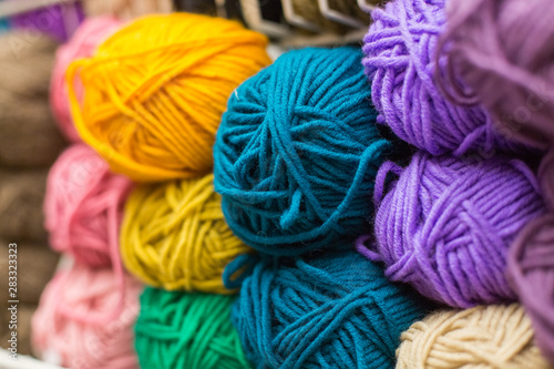 Shelf with a lot of color yarn for diy knitting. Selection of colorful yarn wool on shopfront. Knitting background. Knitting balls of wool, crochet hooks pattern.