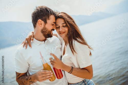 Beautiful couple having fun on the beach, drinking cocktails and smiling.