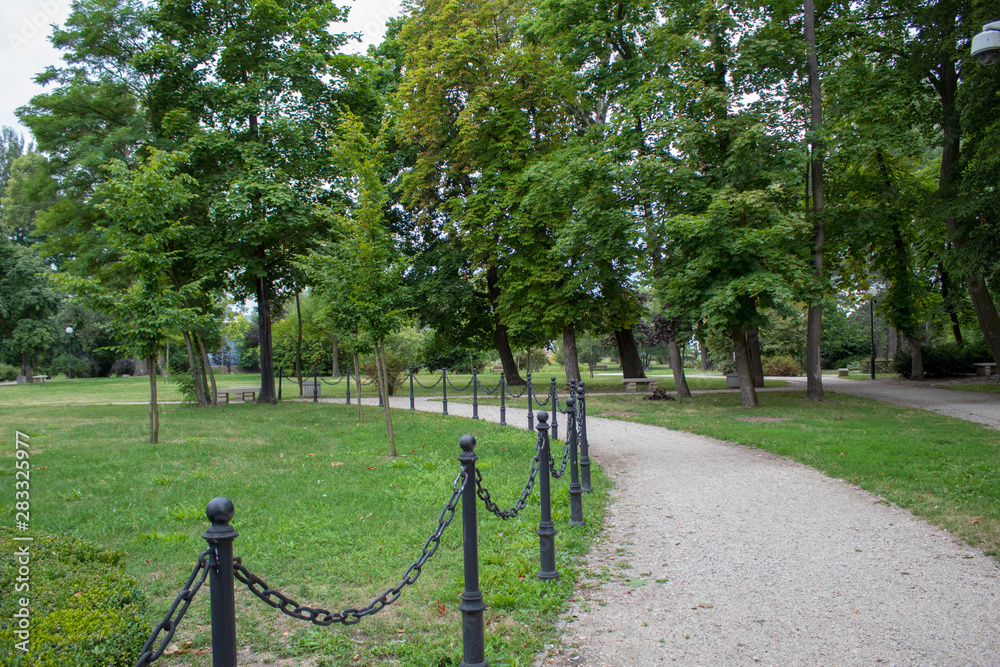 A beautiful, well-kept green European park with shady alleys, a trimmed lawn, decorative bushes and trees on a summer day. A beautiful, well-kept green European park with shady alleys, a trimmed lawn, decorative bushes and trees on a summer day.