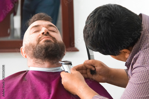 Barbershop. Beard trimming man with mohawk.