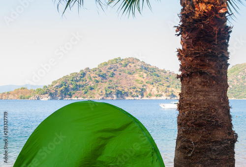 Camping near the sea and mountain in green tent under the palm tree photo