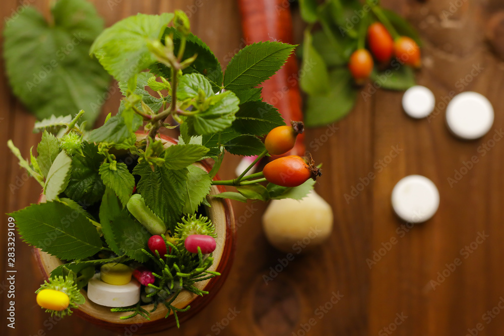 Composition with mortar, fresh herbs and pills on wooden table Composition with mortar, fresh herbs and pills on wooden table
