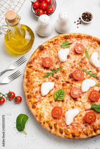 Italian pizza with cheese, tomatoes, olive oil and green salad leaf on white background