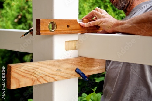 carpentry joints. Wood post, rabbet joint. Mounting the carport. carpenter using a spirit level to connect a spruce wooden beam for Carport outdoor construction. Woodworking and carpentry concept.
