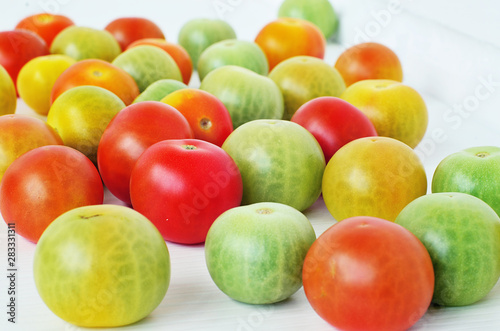 Red  green and yellow tomatoes on white background. Tomatoes of different colors and varieties. Juicy tomatoes on a white table. Colorful vegetables.