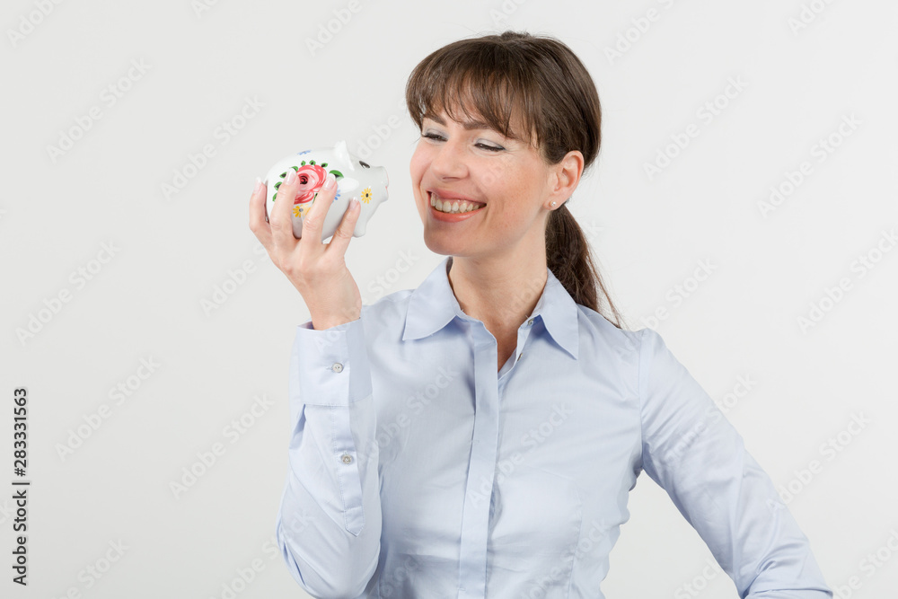 happy woman looks happily at her piggy bank happy woman looks happily at her piggy bank
