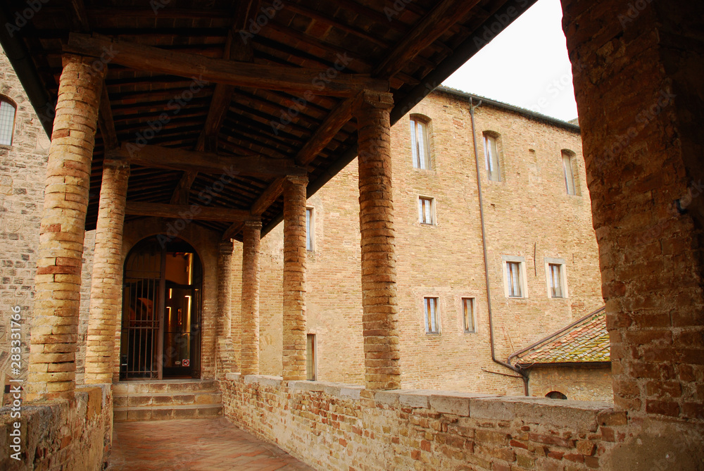 A covered walkway in old brick building in the historic Tuscan hill town of San Gimignano