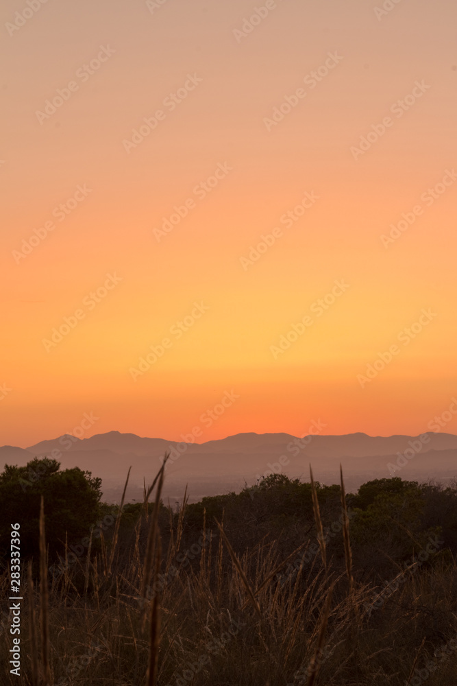 A Portrait image of a sunset behind the mountains during a warm Summer evening in Augsut seen over Alicante City behind the mountains during a warm Summer evening in Augsut seen over Alicante City 