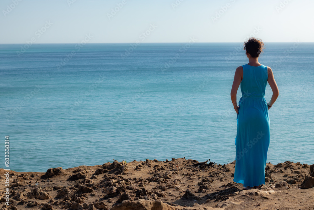 Travel lifestyle. Young woman enjoying ocean view. View from back. Horizon seaview. Copy space. Bali, Indonesia