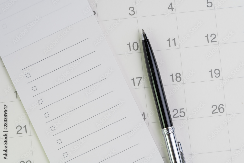 Pen on checklist with checkbox notepad on clean calendar using as special event, planner, important reminder or appointment list concept Pen on checklist with checkbox notepad on clean calendar using as special event, planner, important reminder or appointment list concept