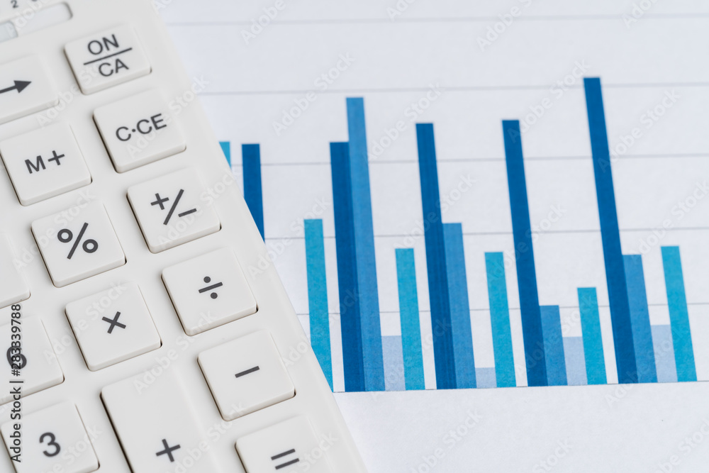 White calculator on blue bar graph reports using as business performance, accounting, financial analysis, profit and loss of company or stock market investment concept White calculator on blue bar graph reports using as business performance, accounting, financial analysis, profit and loss of company or stock market investment concept