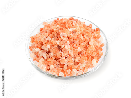 Large crystals of pink himalayan salt in a glass saucer isolated on white background. Himalayan salt is used in cooking, medicine and cosmetology.