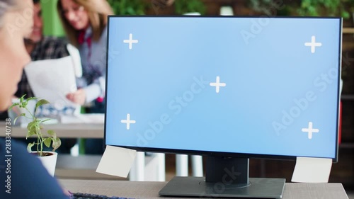 Caucasian business woman typing on her computer in the office. Mock-up display. Coworkers in the background.
