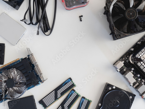top view of computer parts with harddisk, solid state drive, ram, CPU, graphics card, and motherboard on white table background.